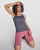 Aida Tank Top in grey paired with pink shorts, featuring a model posing with one arm raised and a logo.
