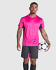 A sports uniform set in vibrant pink and black, featuring a shirt and shorts, held by a model with a soccer ball.