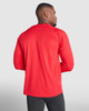A long-sleeved t-shirt in red, shown from the back on a model wearing black pants. The shirt features a branded logo.
