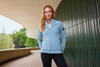 A light blue ladies zip jacket with a slim fit, featuring pockets and a logo, set against a modern architectural background.