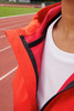 A close-up of a women's sports softshell jacket in vibrant red, featuring a hood and a black zipper.