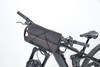 A black bicycle handlebar bag secured to a bike's handlebars, featuring a sleek design and straps for attachment.