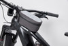 A grey bicycle frame bag sits atop a black bicycle frame, featuring a zip closure and a compact design.