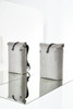 A grey roller backpack with a structured design, featuring a top flap and a logo. Two bags are displayed on a reflective surface.
