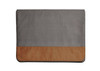 A laptop bag featuring a grey fabric body and a tan leather bottom. It includes a logo on the exterior.