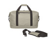A light grey duffle bag with black straps and a detachable padded shoulder strap, featuring a zippered pocket on the front.