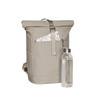 A beige backpack with a roll-top design, featuring a front zip pocket and a drink bottle beside it.