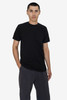 A black short sleeve fine jersey crew tee, worn by a model with hands in pockets, against a plain background.