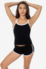 A black spaghetti tank top with white trim, displayed by a model wearing matching black shorts.