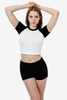 A model poses in a short sleeve baby rib raglan tee with a white body and black sleeves, paired with black shorts.