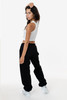 A model wearing black heavy fleece sweatpants paired with a white crop top, showcasing a side view.