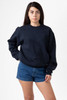 A navy heavy fleece pullover sweater worn by a model, paired with denim shorts. The sweater has a logo.