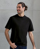 An oversized black T-shirt displayed on a smiling man, featuring a simple design and short sleeves.