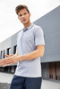A grey polo shirt featuring a collar and short sleeves, displayed by a man outdoors. The shirt has a logo.