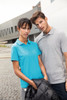A blue polo shirt and a grey polo shirt worn by a woman and a man, with a black jacket draped over the woman's arm.