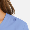 A women's mock wrap top in light blue with a loop detail on the shoulder. Features a sleek neckline design.