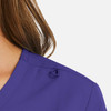 A close-up of a women's mock wrap top in purple, featuring a decorative loop on the shoulder.