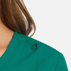 A close-up of a teal women's mock wrap top featuring a unique shoulder detail and a logo.