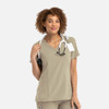 A women's mock wrap top in beige, featuring a V-neck design and a logo, styled with a stethoscope.