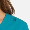 A woman's mock wrap top in vibrant teal, featuring a loop detail on the shoulder and a smooth fabric texture.