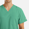 A green v-neck top with four pockets designed for men, featuring a logo on the shoulder.