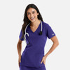 A woman wearing a purple double V-neck top with a stethoscope around her neck and pockets on the front.