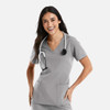A woman wearing a grey double V-neck top with a stethoscope around her neck, smiling and posing.