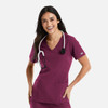 A woman wearing a burgundy double V-neck top with a stethoscope around her neck and pockets on the front.