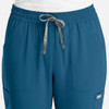 A pair of women's full elastic pull-on pants in teal, featuring a drawstring and side pockets. A logo is present.