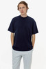 A short sleeve crewneck tee in navy, worn by a model with hands in pockets, paired with grey pants.
