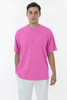 A man wears a bright pink short sleeve crewneck tee, paired with white trousers. The tee has a subtle logo.