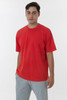 A red short sleeve crewneck tee displayed on a model, paired with grey trousers. The shirt has a logo.