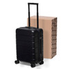 A black hardcase trolley with four wheels and a retractable handle, positioned next to a cardboard box.