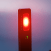 A rechargeable work light with a red light and a green indicator, featuring a sleek black design and a logo.