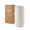 A white coffee cup sits next to its cardboard packaging, featuring a logo and a sleek design.