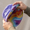 A purple reversible bucket hat with a rainbow-patterned interior and a logo.