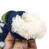 A hand holding a blue sock with a fluffy white interior and green detailing, featuring a decorative pattern.