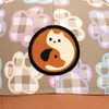 A cap featuring a light brown fabric with a playful paw print pattern and a circular patch displaying a cat and dog design.