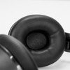 A close-up of black cushioned ear cups of wireless headphones, featuring smooth material and a sleek design.