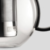 A glass tea press featuring a stainless steel infuser and a black handle, with a logo on the body.