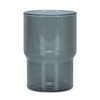 A drink tumbler in a transparent smokey grey colour with a distinctive curved design. Includes a logo.