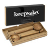 Wooden salad servers presented in a stylish box, featuring a fork and spoon design. The packaging has a logo.