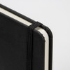 A5 weekly diary in black with a textured cover and elastic closure, featuring rounded corners.