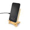 A bamboo charging stand holds a smartphone that is plugged in and indicating a charging status.
