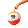 A beach ball featuring orange, white, and red segments with a colourful logo, held by a hand.