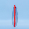 A red plastic ball pen stands upright against a light blue background, featuring a simple design and a logo.