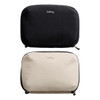 A black and a beige tech kit with zippers, both featuring a logo on the front.