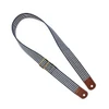 A striped shoulder strap in navy and white with brown leather ends and a gold buckle. It has a stylish design.