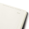A Moleskine 2027 weekly planner in navy blue with blank pages and a branding logo on the cover.