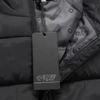 A black unisex puffer vest with a zip and an inner lining featuring a branding logo. A tag is attached.
